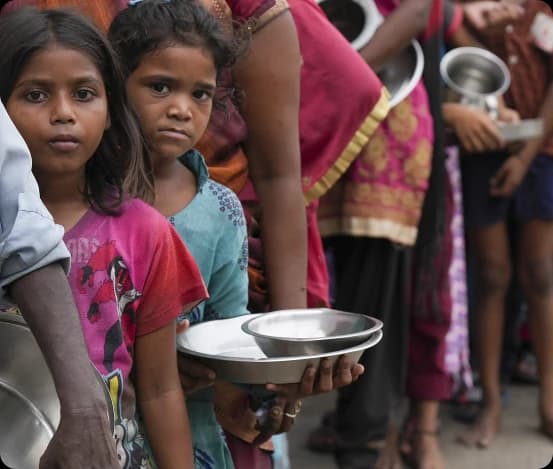 Children waiting in line with empty metal bowls